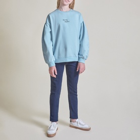 Model wearing Street Monkey blue sweat top with small chest print, styled with navy slim-fit trousers and white trainers.