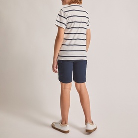 Model wearing Street Monkey white stripe T-shirt, styled with navy shorts and white trainers, seen from behind.