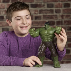 Boy holding Superheroes Savage Smash Hulk green action figure, smiling, with brick wall background