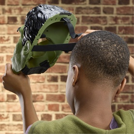 Child holding up Superheroes Savage Hulk Talk'n Electronic Mask, showing green and grey interior with adjustable head straps.