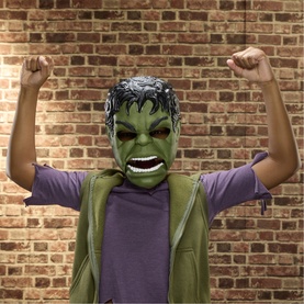 Child wearing Superheroes Savage Hulk Talk'n Electronic Mask, green Hulk face mask with roaring expression, fists raised, brick wall background