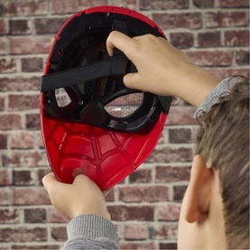 Child holding Superheroes Spider-Man Wisecrackin' Glow Mask, red and black with web detail, viewed from behind against brick wall