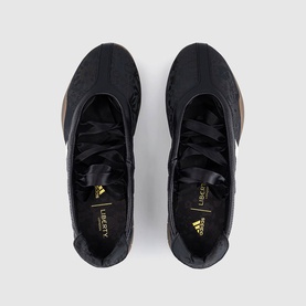Adidas trainers in black with gold Adidas logo and Liberty London branding, top-down view showing lace-up front and textured upper
