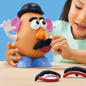 Toy Story Mr. Potato Head toy with child attaching facial features, including moustache and mouth pieces on table