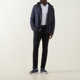 Model wearing Herno white cotton casual shirt, styled with navy hooded jacket, black trousers and navy trainers.
