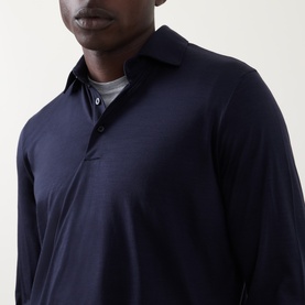 Model wearing Herno Jersey Long-Sleeved Polo Shirt in navy blue wool, showing polo collar and button fastenings, styled with grey crew-neck