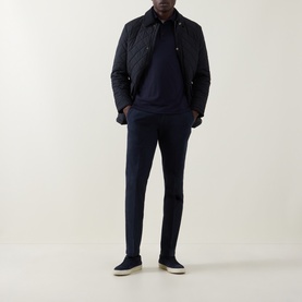 Model wearing Herno Jersey Long-Sleeved Polo Shirt in blu navy, styled with navy quilted jacket, matching trousers and cream sole trainers.