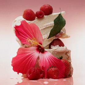 PHLUR Berry Cream Hair and Body Mist 90ml lifestyle shot with layered meringue cake, fresh strawberries, raspberries and pink hibiscus flower