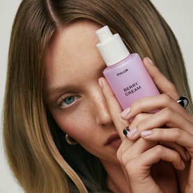 Model with PHLUR Berry Cream Hair and Body Mist 90ml, holding lilac bottle close to face, wearing gold hoop earring