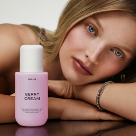 Model with PHLUR Berry Cream Hair and Body Mist 240ml in lilac bottle, wearing a silver bracelet