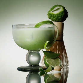 PHLUR Matcha Milk Hair and Body Mist 90ml styled with matcha whisk, lime, bergamot and mint in a frosted green cocktail glass