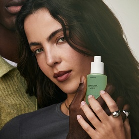 Model with PHLUR Matcha Milk Hair and Body Mist 90ml in green bottle with white dropper cap, silver ring visible on hand