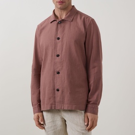 Model wearing Profuomo Garment-Dyed Overshirt in clay, featuring pointed collar, button fastenings and long sleeves, styled with light linen trousers