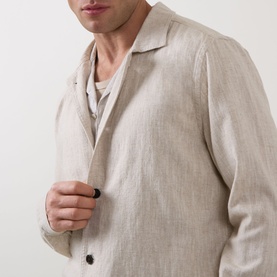 Model wearing Profuomo Notched Collar Overshirt in beige linen-cotton, styled over a light crew-neck tee, with notched collar and button fastenings