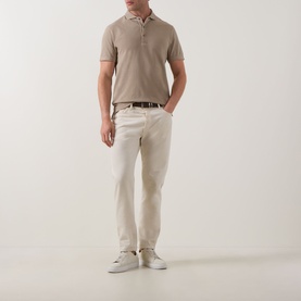 Model wearing Profuomo Garment-Dyed Polo Shirt in beige, styled with cream trousers, dark belt and white trainers.