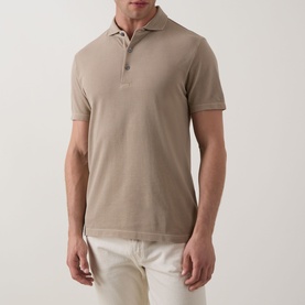 Model wearing Profuomo Garment-Dyed Polo Shirt in beige, short sleeves, polo collar with button fastenings, styled with cream trousers