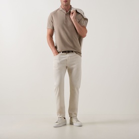 Model wearing Profuomo Garment-Dyed Polo Shirt in beige with cream chinos, a woven belt, and white trainers.