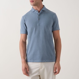 Model wearing Profuomo Garment-Dyed Polo Shirt in grey blue, short sleeves, zip placket, polo collar, styled with white trousers