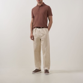 Model wearing Profuomo Clay Garment-Dyed Polo Shirt with cream wide-leg trousers and brown loafers.