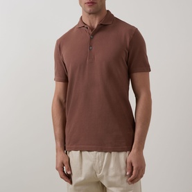 Model wearing Profuomo Garment-Dyed Polo Shirt in clay, short sleeves, polo collar, button fastenings, styled with cream trousers