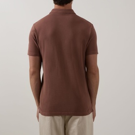 Model wearing Profuomo Garment-Dyed Polo Shirt in clay, back view, short sleeves, polo collar, styled with beige trousers