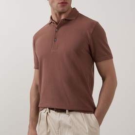 Model wearing Profuomo Garment-Dyed Polo Shirt in clay, short sleeves, polo collar with button fastenings, styled with cream trousers