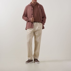 Model wearing Profuomo Clay Garment-Dyed Polo Shirt, styled with a pink overshirt, cream trousers and brown trainers.
