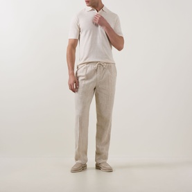 Model wearing Profuomo Solid Knitted Polo Shirt in Off White with beige linen drawstring trousers and matching slip-on shoes.
