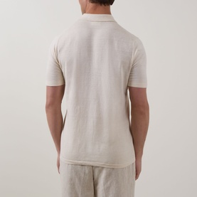 Model wearing Profuomo Solid Knitted Polo Shirt in Off White, back view, paired with light linen trousers