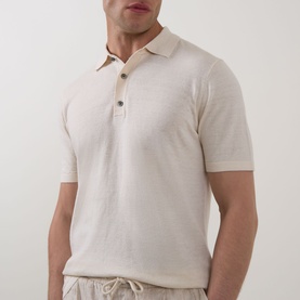 Model wearing Profuomo Solid Knitted Polo Shirt in off white linen-cotton, with polo collar and short sleeves, styled with light drawstring trousers.
