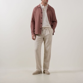 Model wearing Profuomo Solid Knitted Polo Shirt in Off White, styled with a dusty pink overshirt and stone linen trousers.