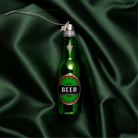 Green glass beer bottle Christmas tree ornament with silver star hanger, displayed on dark green satin fabric