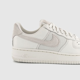 Nike Air Force 1 trainer in Phantom white, featuring mesh Swoosh detail, leather upper, and off-white cupsole, close-up side view.