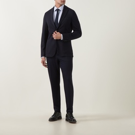 Model wearing Hugo Boss dark blue wool-blend jacket with matching trousers, white shirt, navy tie, and black leather shoes.