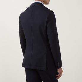 Model wearing Hugo Boss dark blue wool-blend jacket, rear view, showing tailored back seam and two-button cuffs, styled with white shirt.