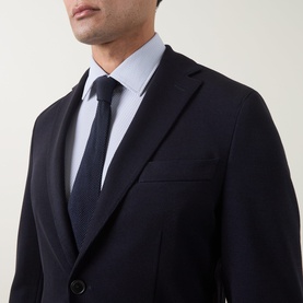 Model wearing Hugo Boss dark blue wool-blend jacket with notch lapels, styled with a light blue shirt and navy tie.