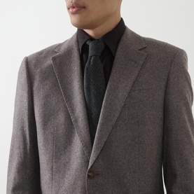 Model wearing Hugo Boss dark brown wool blend suit jacket with notch lapels and single button detail, styled with black shirt and tie