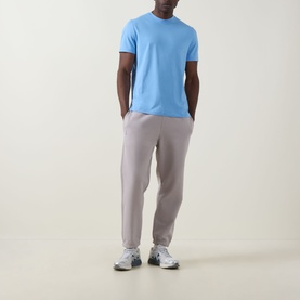 Model wearing On Running Club Collective Logo Sweat Pants in Ore, styled with a light blue T-shirt and white trainers.