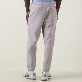Model wearing On Running Club Collective Logo Sweat Pants in Ore, cuffed style, rear view, styled with white trainers