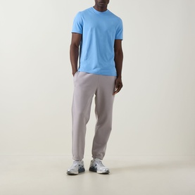 Model wearing On Running Club Collective Logo Sweat Pants in Ore, styled with a light blue T-shirt and white trainers.
