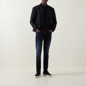Model wearing Boss Black Casual black cotton polo, styled with dark navy jeans, black bomber jacket and navy low-top trainers
