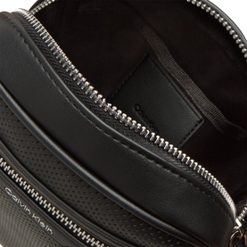 Calvin Klein black crossbody bag interior view, showing main zipped compartment and inner pocket with silver-tone zip detailing