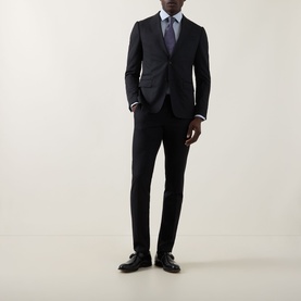 Model wearing Calvin Klein The Poplin Dotted Shirt in Blue Dot, styled with a dark suit, tie, and black leather shoes.