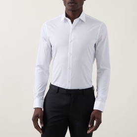 Model wearing Calvin Klein The Poplin Slim Fit Shirt in white, slim cut with pointed collar and single cuffs, styled with black trousers.