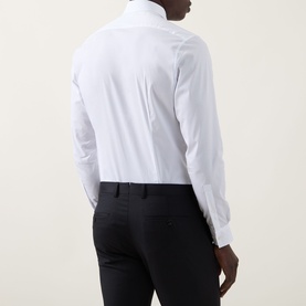 Model wearing Calvin Klein The Poplin Slim Fit Shirt in white, back view, styled with black slim-fit trousers. Single cuff, long sleeves visible.