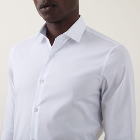 Model wearing Calvin Klein The Poplin Slim Fit Shirt in white, featuring a pointed collar and slim-fit silhouette with button fastenings.