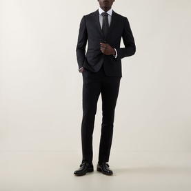 Model wearing Calvin Klein The Poplin Slim Fit Shirt in white, styled with black slim-fit suit, tie, and black dress shoes.