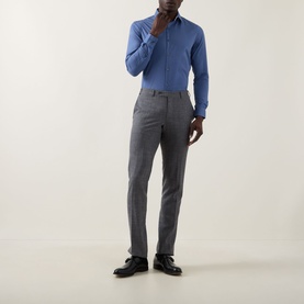 Model wearing Calvin Klein The Poplin Slim Fit Shirt in blue with grey tailored trousers and black dress shoes.