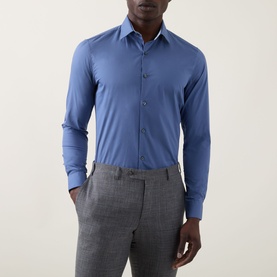 Model wearing Calvin Klein The Poplin Slim Fit Shirt in blue, slim cut with pointed collar and button fastenings, styled with grey trousers