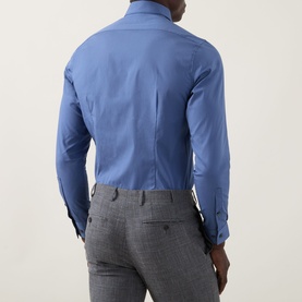 Model wearing Calvin Klein The Poplin Slim Fit Shirt in blue, back view, styled with grey check trousers.